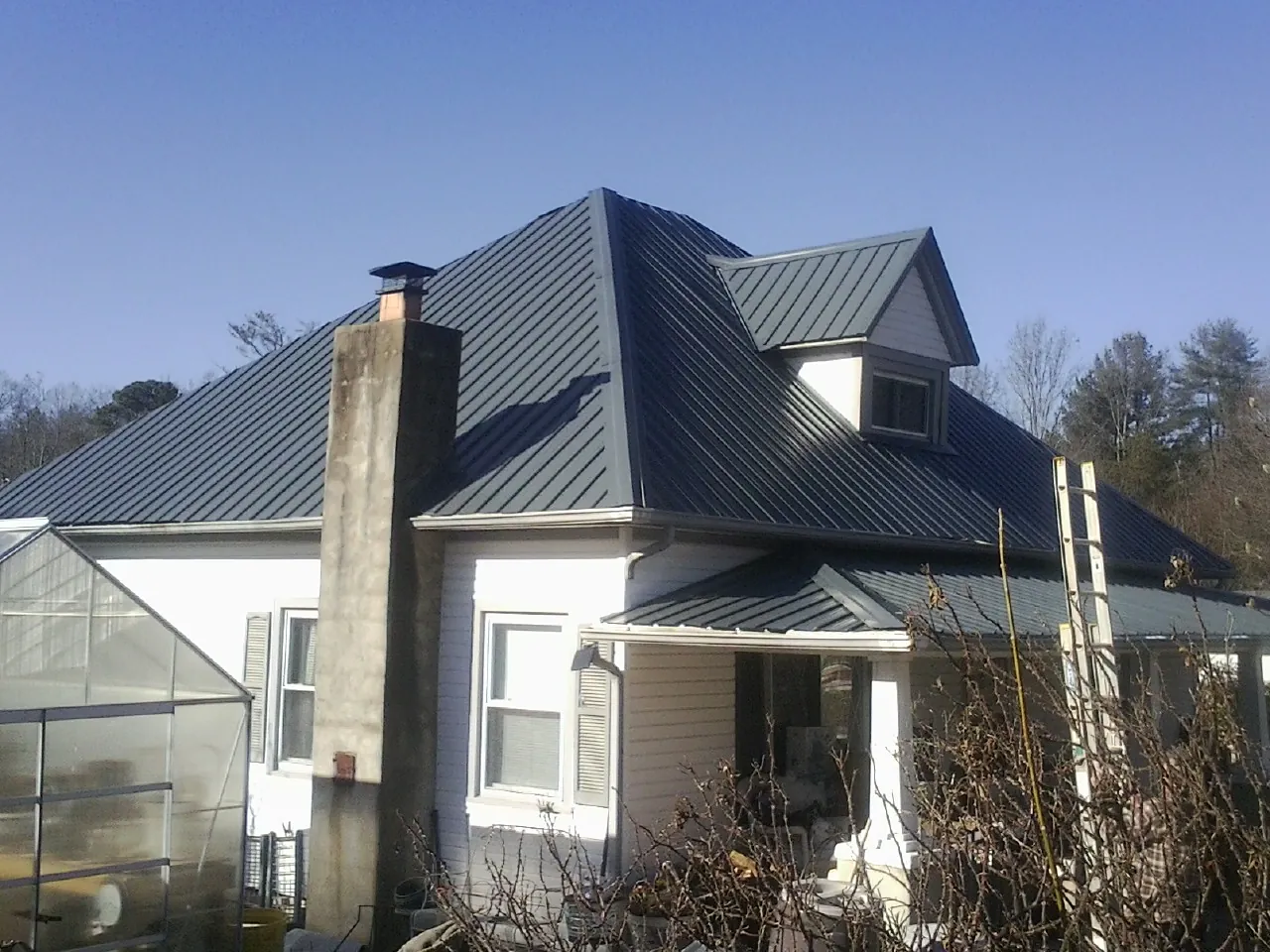 Dark blue standing seam metal roof on a white farmhouse with dormer — Slate & Tile Roof Repair by Roofing Brothers in Brookdale