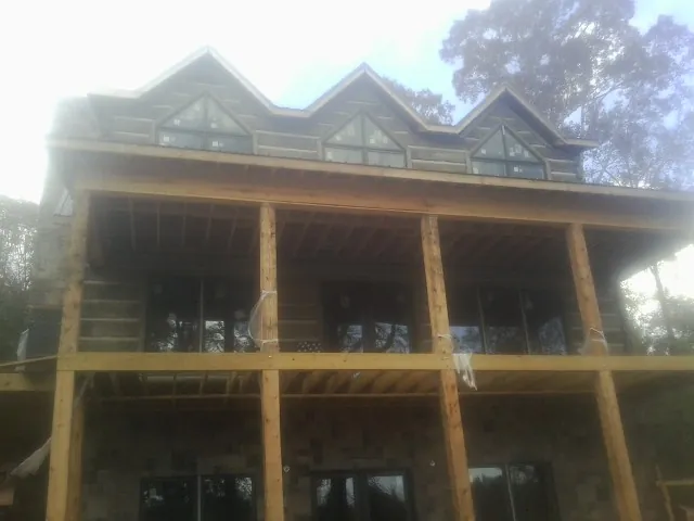 Dormers and porch framing on a large log home under construction — Roof Coating work by our crew in Brookdale