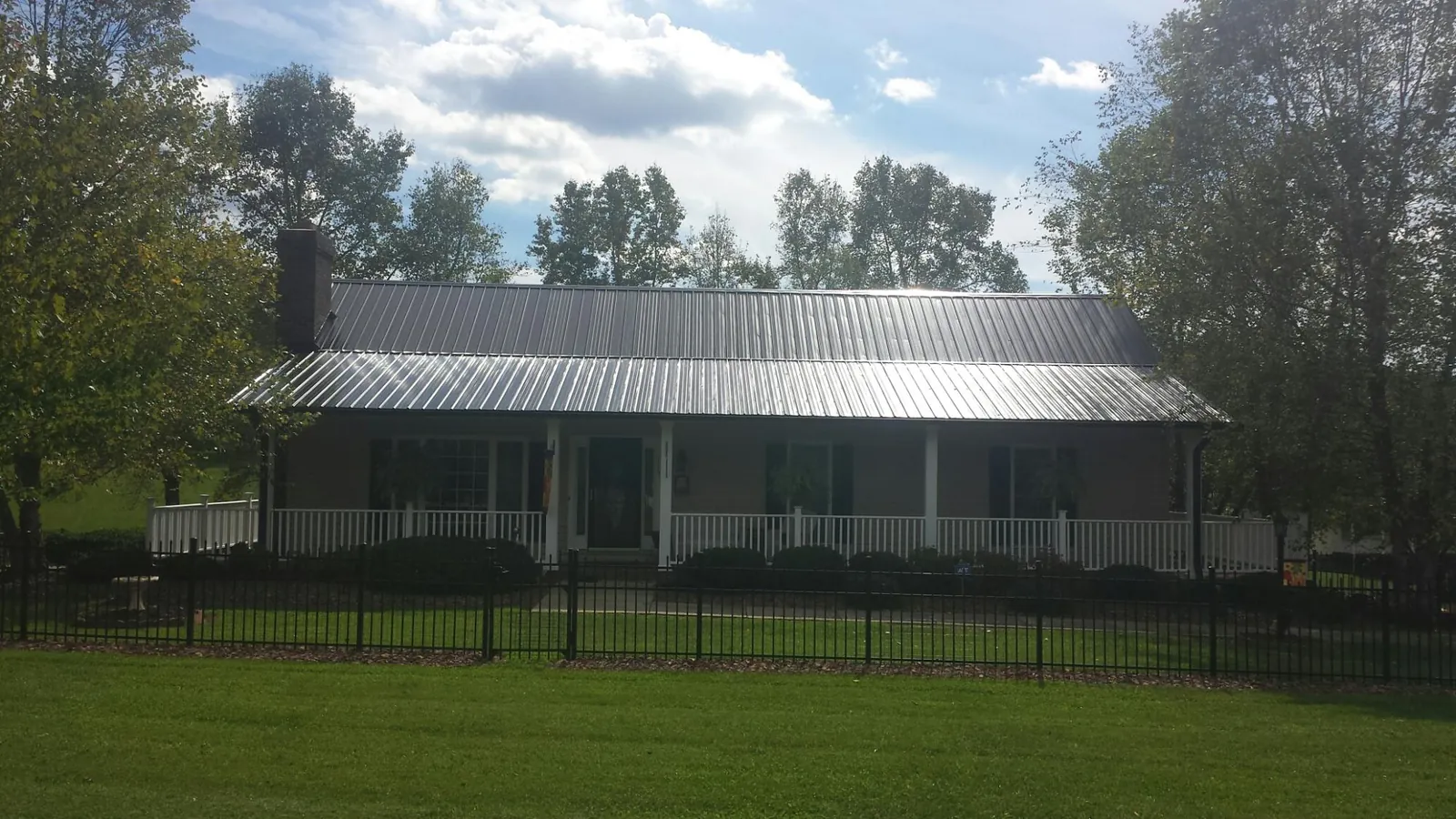 Gray metal roof on a brick ranch with a full width front porch — Gutter Guard Installation work by our crew in Brookdale