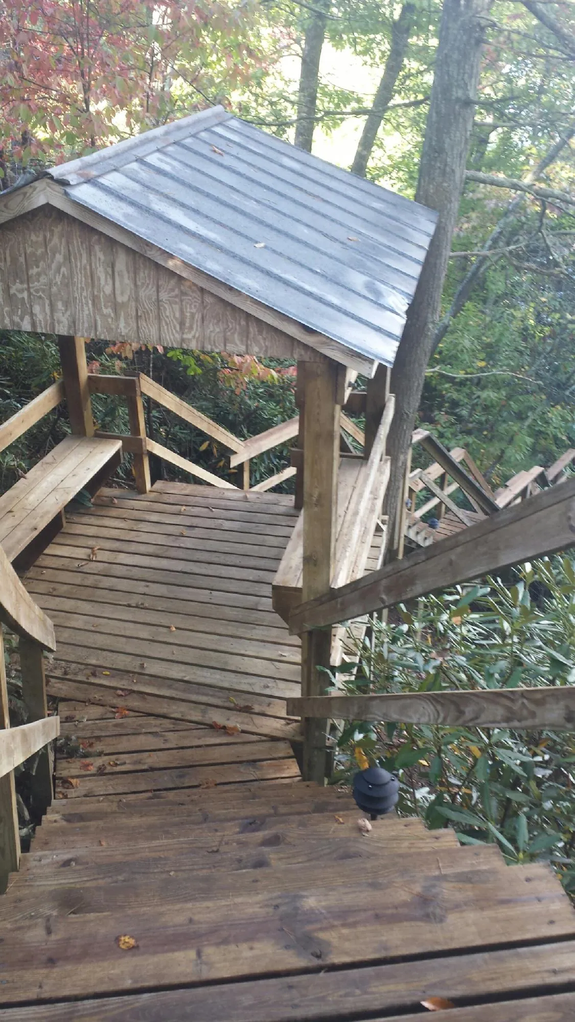 Metal roofed shelter over wooden steps on a wooded walkway — Skylight Repair & Installation work by our crew in Brookdale