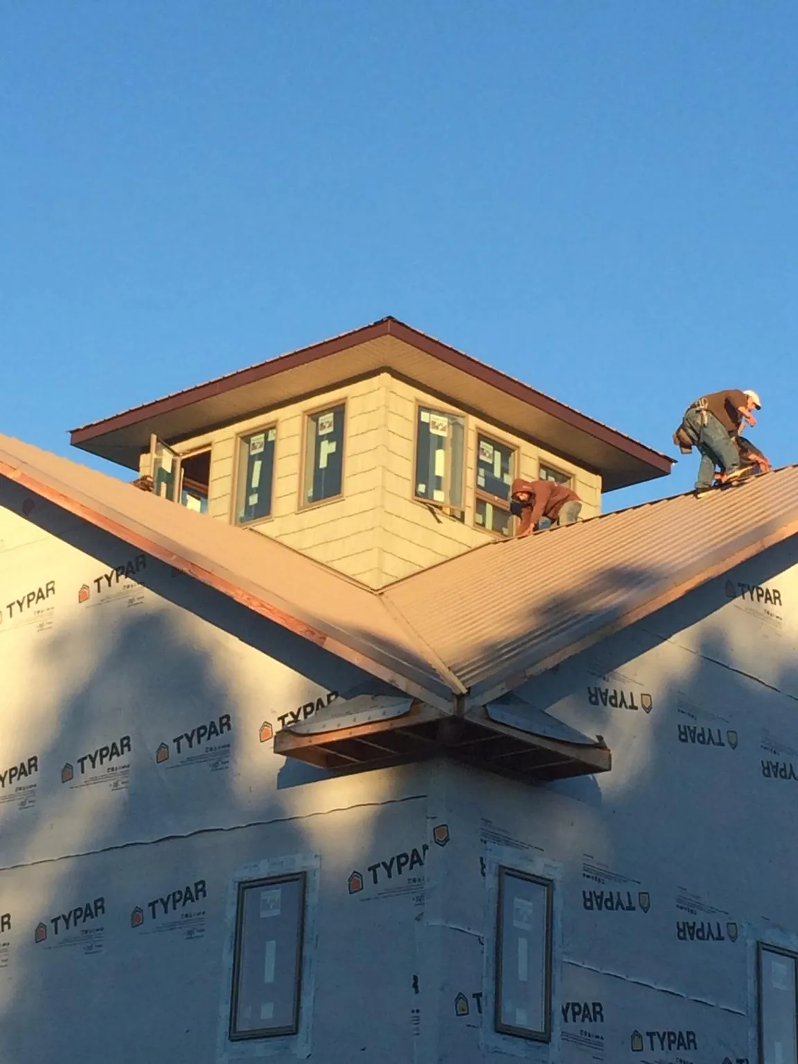 Roofers working around a rooftop cupola on a new metal roof at sunset — Roof Waterproofing in Brookdale by Roofing Brothers
